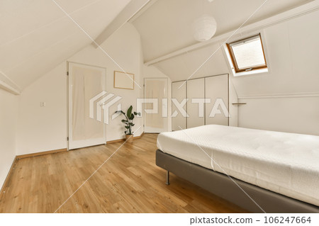 a bedroom with white walls and wood flooring the room is well lit by natural light from the skylight 106247664