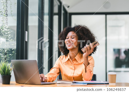 Cheerful young African American pretty woman, entrepreneur in casual wear, smiling, using smartphone and working in a modern office. Cheerful young African American pretty woman, entrepreneur in casual wear, smiling, using smartphone and working in a modern office. 106249837
