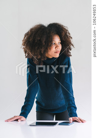 Studio portrait of confident young African American woman smiling at camera standing arm crossed on white background. 106249853