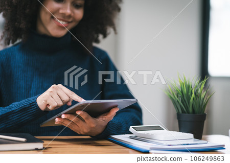 Successful young African American pretty woman, entrepreneur in casual wear, smiling, working on laptop in a modern office. 106249863