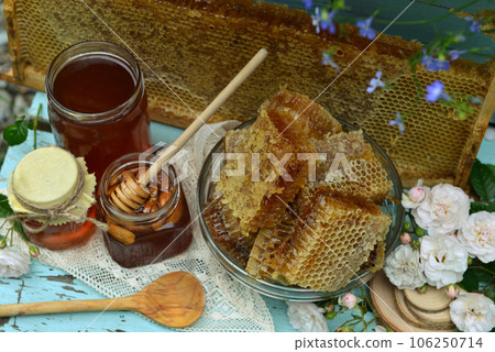 Still life with natural honey in jar, honeycomb cut in pieces, dipper and spoon on wooden background outside. Countryside summer rural background, vintage concept, healthy food Still life with natural honey in jar, honeycomb cut in pieces, dipper and spoon on wooden background outside. Countryside summer rural background, vintage concept, healthy food 106250714