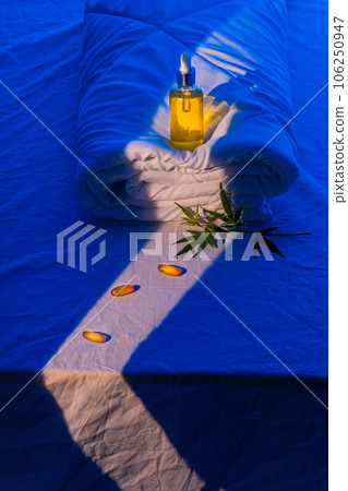 Bottle of CBD oil, and marijuana leaf on blanket podium in beam of moonlight Bottle of CBD oil, and marijuana leaf on blanket podium in beam of moonlight 106250947