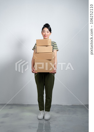 Happy asian woman holding pile of boxes, concept of delivery, shopping or business, white background Happy asian woman holding pile of boxes, concept of delivery, shopping or business, white background 106252110