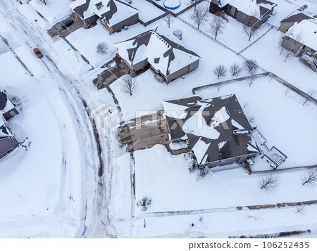 Aerial drone view of a snow covered suburban residential neighborhood with rows of white roofs and houses. Aerial drone view of a snow covered suburban residential neighborhood with rows of white roofs and houses. 106252435
