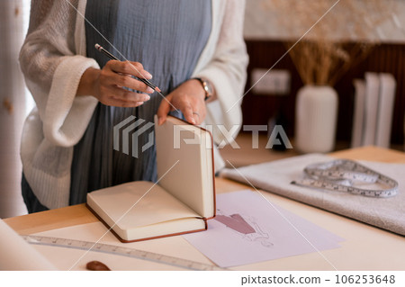 Asian tailor women creative and designing new fashion collection while drawing sketch in notebook Asian tailor women creative and designing new fashion collection while drawing sketch in notebook 106253648