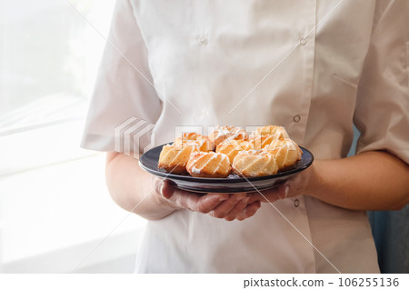 Cropped image of Woman chef holding fresh and tasty freshly baked coconut cookies. Cropped image of Woman chef holding fresh and tasty freshly baked coconut cookies. 106255136