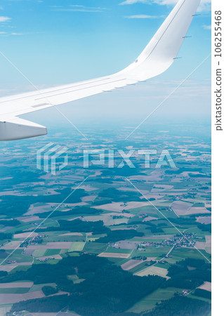 Wings of an airplane and a vast expanse of green land Wings of an airplane and a vast expanse of green land 106255468