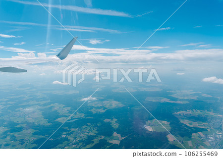 Wings of an airplane and a vast expanse of green land Wings of an airplane and a vast expanse of green land 106255469