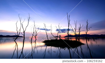 beautiful sunset on the reservoir , reflection of silhouettes dry tree , landscape thailand beautiful sunset on the reservoir , reflection of silhouettes dry tree , landscape thailand 106259162