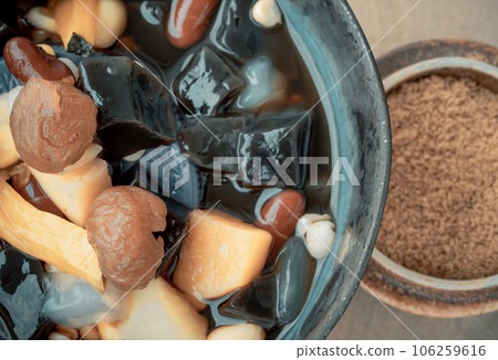 Close-up of Black Grass Jelly is including Nuts, Cereals, Red beans, Ginkgo, Pumpkin, Corn kernels, Millet, Sweet potato, Palm seed and Jelly in Longan Juice in Ceramic bowl which is served with Brown Close-up of Black Grass Jelly is including Nuts, Cereals, Red beans, Ginkgo, Pumpkin, Corn kernels, Millet, Sweet potato, Palm seed and Jelly in Longan Juice in Ceramic bowl which is served with Brown 106259616