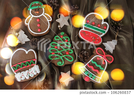 Banner for Christmas and New Year gingerbread. Christmas trees, toys, snowmen, garlands on a background of brown silk fabric. Bright bokeh. 106260837