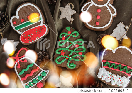 Banner for Christmas and New Year gingerbread. Christmas trees, toys, snowmen, garlands on a background of brown silk fabric. Bright bokeh. Banner for Christmas and New Year gingerbread. Christmas trees, toys, snowmen, garlands on a background of brown silk fabric. Bright bokeh. 106260841