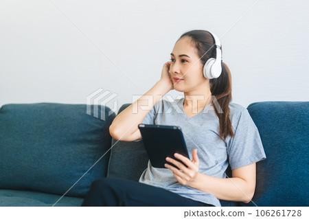 Young adult asian woman wear headphone listen music and relax using digital tablet 106261728