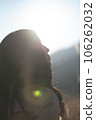 A black-haired woman looking up in the backlight 106262032