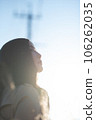 A black-haired woman looking up in the backlight 106262035