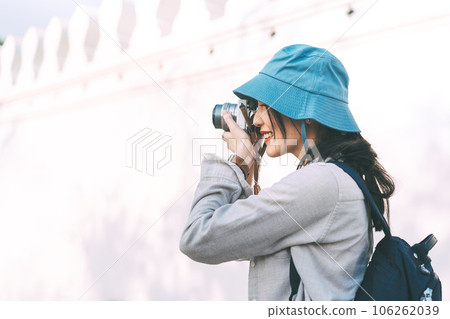 Young adult asian woman traveller wear blue hat and backpack travel in city using camera Young adult asian woman traveller wear blue hat and backpack travel in city using camera 106262039