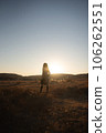 A woman in a trench coat floating in the meadow in the sunset 106262551