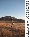 A woman in a trench coat is standing looking at me in Kusasenri, Aso. 106262552