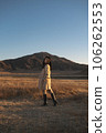A woman in a trench coat is standing looking at me in Kusasenri, Aso. 106262553