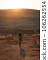A woman in a trench coat stands at Kusasenri in the setting sun 106262554