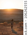 A woman in a trench coat stands at Kusasenri in the setting sun 106262555