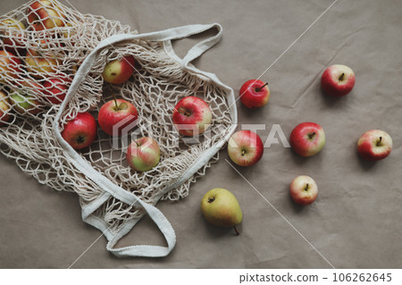 Red apples in a eco mesh shopping bag on a paper background. Zero waste, no plastic. Autumn flatlay 106262645