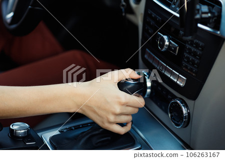 Young woman driver hand holds close up gear shift knob car Young woman driver hand holds close up gear shift knob car 106263167