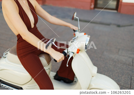 Young blond woman model riding on motorbike moped scooter in city street hold hand 106263201