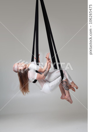 Beautiful girl and an athletic man in a white sport suits are performing an acrobatic elements in a studio. Beautiful girl and an athletic man in a white sport suits are performing an acrobatic elements in a studio. 106265475