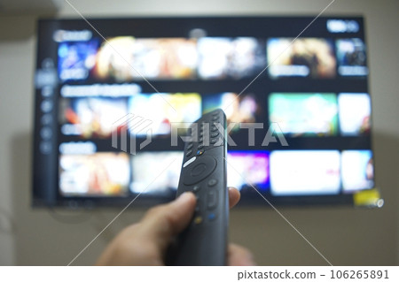 Hand with TV remote control, switching TV series from streaming service platform. The new way of enjoying entertainment at home. 106265891