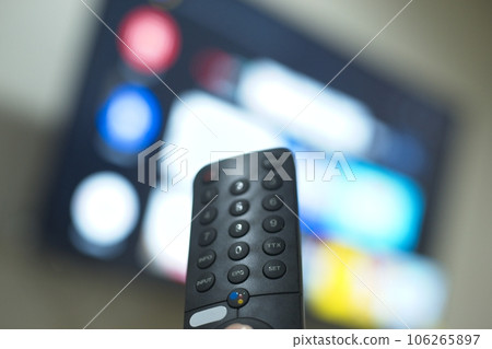 Hand with TV remote control, switching TV series from streaming service platform. The new way of enjoying entertainment at home. Hand with TV remote control, switching TV series from streaming service platform. The new way of enjoying entertainment at home. 106265897
