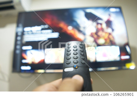 Hand with TV remote control, switching TV series from streaming service platform. The new way of enjoying entertainment at home. 106265901