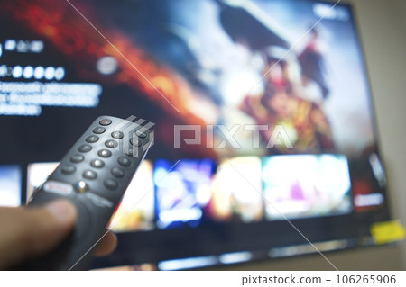 Hand with TV remote control, switching TV series from streaming service platform. The new way of enjoying entertainment at home. 106265906