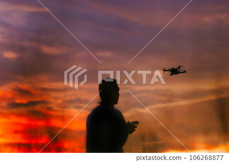 Silhouette of a boys piloting a drone on A Rural Setting on sunset Silhouette of a boys piloting a drone on A Rural Setting on sunset 106268877