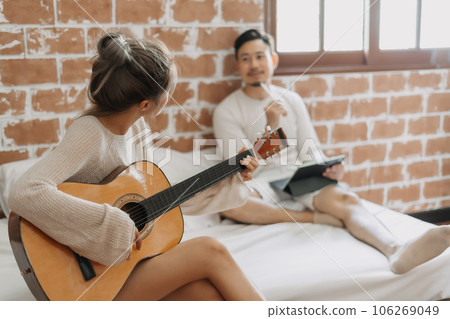 Woman play guitar for man in happy warm day off. Concept of hobby activity. 106269049