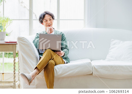 man using computer on sofa in living room 106269314