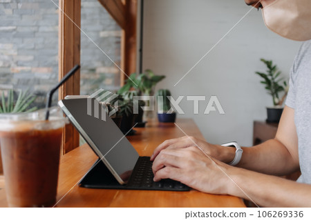 Asian freelanceman wears mask while working in the coffee cafe. Asian freelanceman wears mask while working in the coffee cafe. 106269336