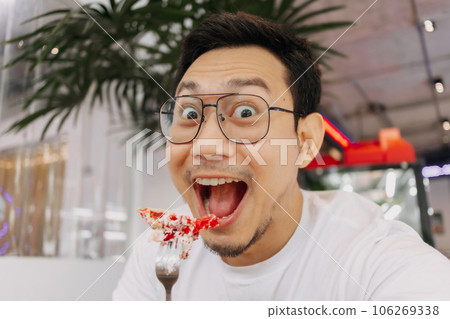 Funny happy face of man eating and putting cake into his mouth. Funny happy face of man eating and putting cake into his mouth. 106269338