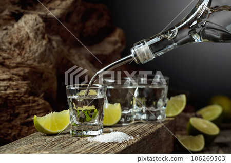 Tequila is poured from a bottle into a glass. 106269503