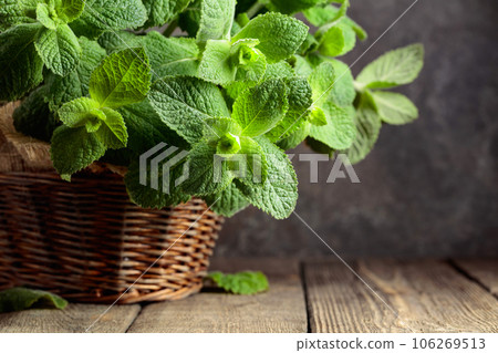 Fresh mint in a basket on an old wooden table. Fresh mint in a basket on an old wooden table. 106269513