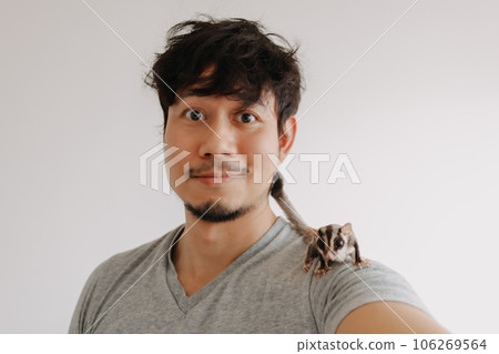Close up of happy man with his Sugar Glider pet climbing around his head. Close up of happy man with his Sugar Glider pet climbing around his head. 106269564