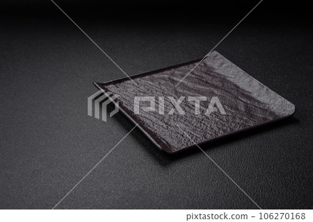 Empty black square ceramic plate on dark concrete background 106270168