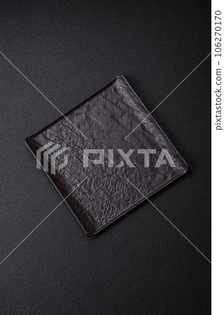 Empty black square ceramic plate on dark concrete background 106270170