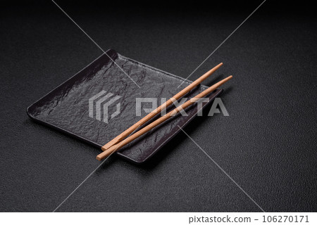Empty black square ceramic plate on dark concrete background 106270171
