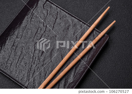 Empty black square ceramic plate on dark concrete background 106270527