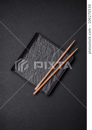 Empty black square ceramic plate on dark concrete background 106270530