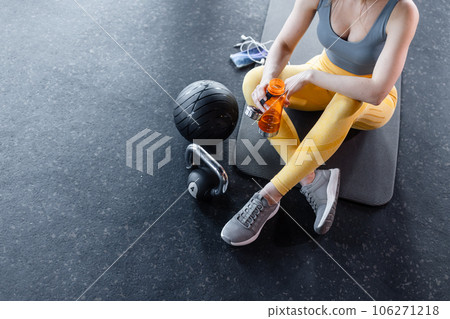 beautiful woman sitting gym floor beside kettle bell 106271218