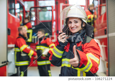 Beautiful fire fighter woman with her helmet standing in the firehouse 106271224