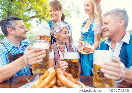Group of friends in beer garden toasting to camera 106271226
