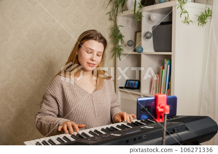 Woman teaching her student to play piano and recording lesson online. 106271336